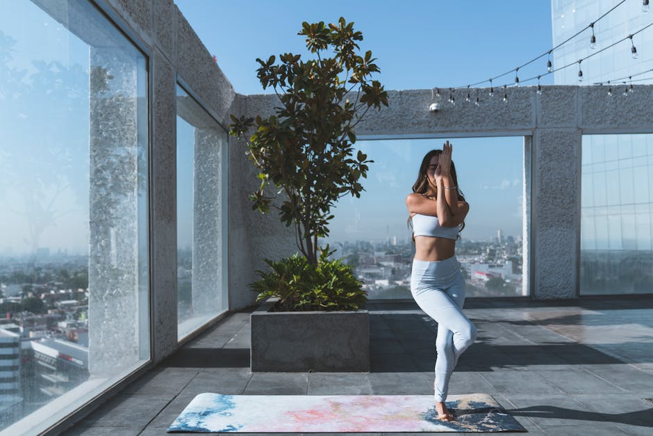 A focused person meditating in a seated yoga pose on a city view balcony.